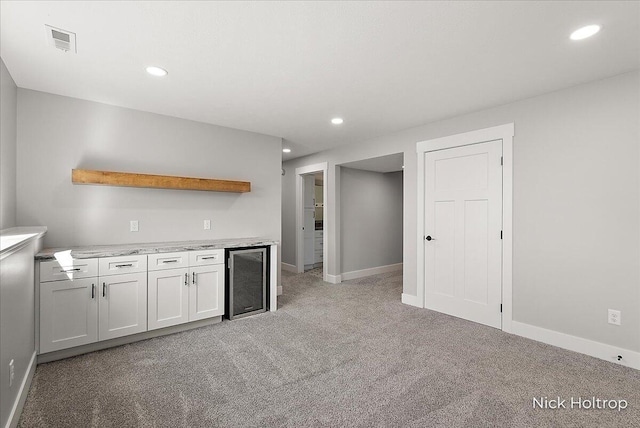 kitchen featuring wine cooler, open shelves, visible vents, light carpet, and baseboards