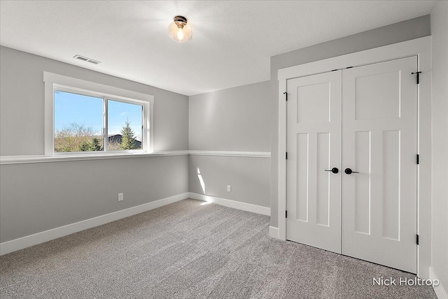 unfurnished bedroom featuring a closet, carpet, visible vents, and baseboards