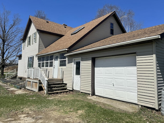 back of house featuring a garage and roof with shingles