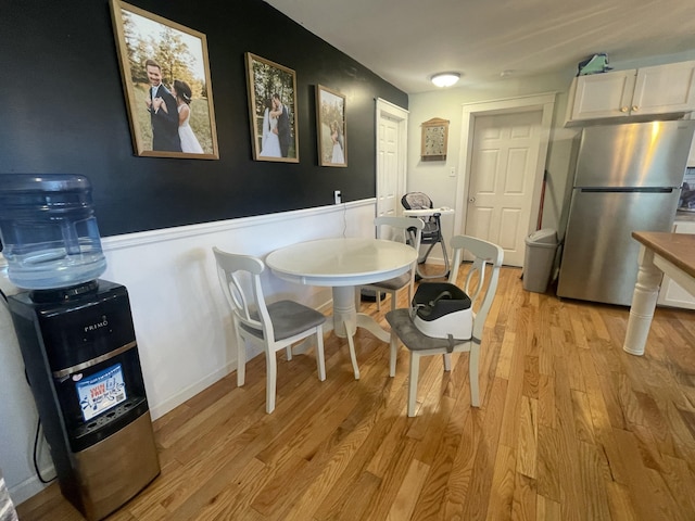 dining space with light wood-style flooring and wainscoting