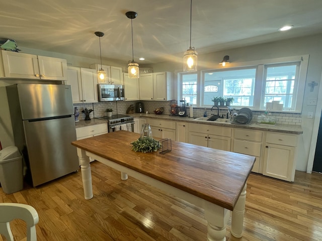 kitchen featuring wood counters, backsplash, white cabinetry, and stainless steel appliances