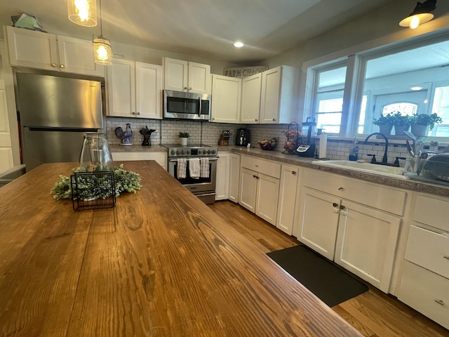 kitchen with stainless steel appliances, a sink, dark wood-type flooring, wood counters, and tasteful backsplash
