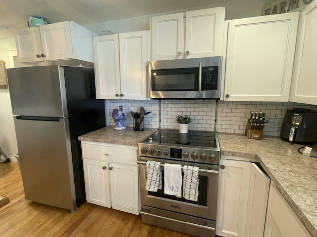 kitchen with tasteful backsplash, light countertops, appliances with stainless steel finishes, light wood finished floors, and white cabinetry
