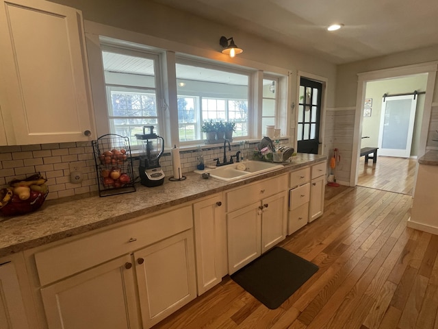 kitchen featuring recessed lighting, light wood finished floors, backsplash, a sink, and white cabinetry