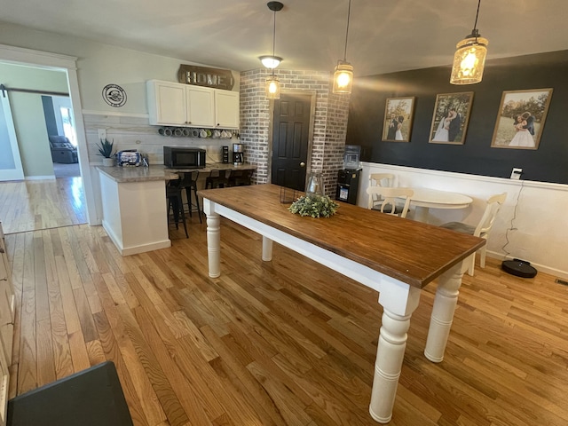 dining room with light wood-style flooring and wainscoting