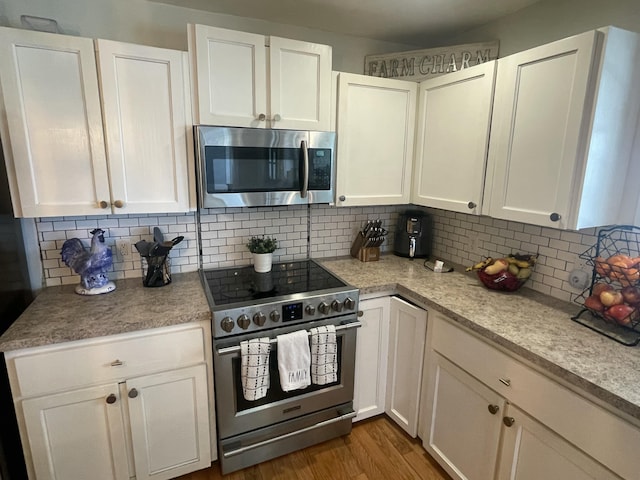 kitchen featuring light countertops, wood finished floors, tasteful backsplash, appliances with stainless steel finishes, and white cabinetry