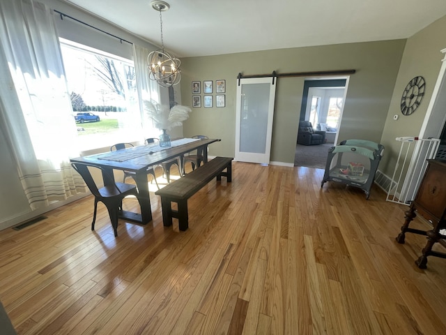 dining area with light wood-style flooring, visible vents, a notable chandelier, and a healthy amount of sunlight
