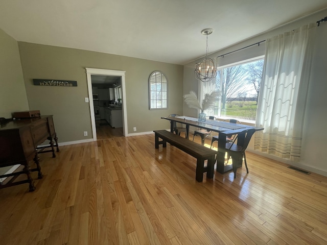 dining space with baseboards, a chandelier, visible vents, and light wood-type flooring