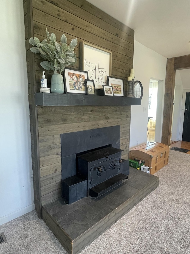 interior details with visible vents, carpet, wood walls, a fireplace, and a wood stove