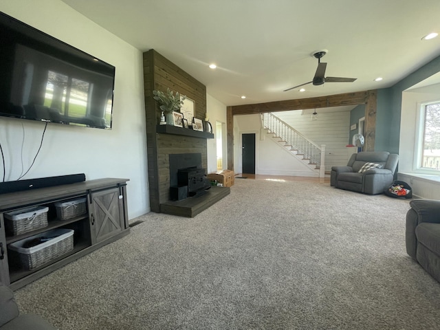 carpeted living room featuring a ceiling fan, a wood stove, stairs, and recessed lighting