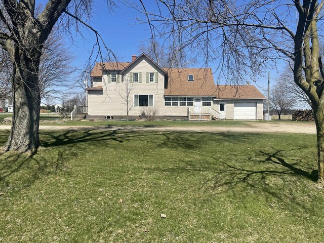 view of front of house with an attached garage, dirt driveway, a chimney, and a front lawn