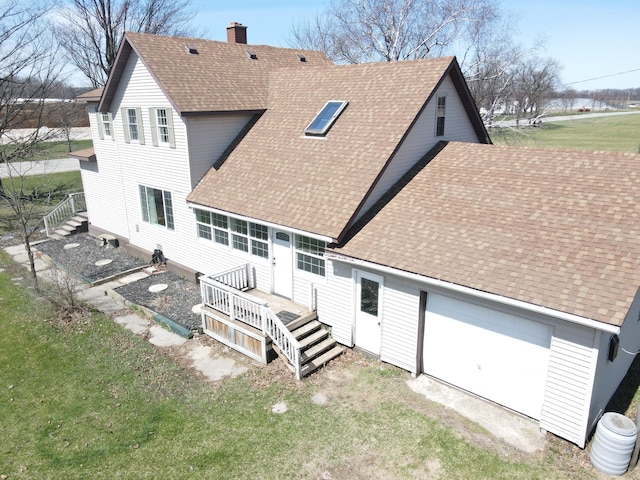 back of house with a chimney, roof with shingles, and a lawn
