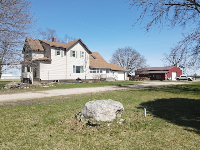 exterior space featuring dirt driveway, a chimney, a front lawn, roof with shingles, and a garage