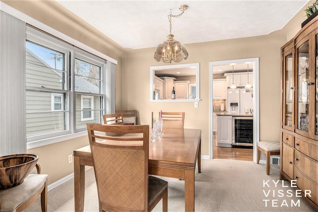 2139 Anderson Dr SE, Grand Rapids, MI 49506 - dining space featuring a chandelier, beverage cooler, baseboards, and light colored carpet