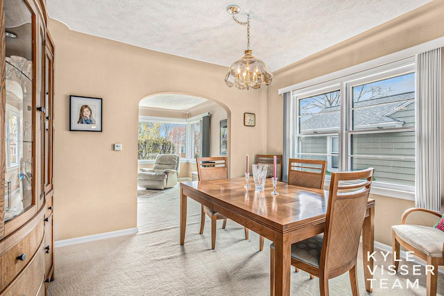 2139 Anderson Dr SE, Grand Rapids, MI 49506 - carpeted dining space with arched walkways, a textured ceiling, baseboards, and a notable chandelier