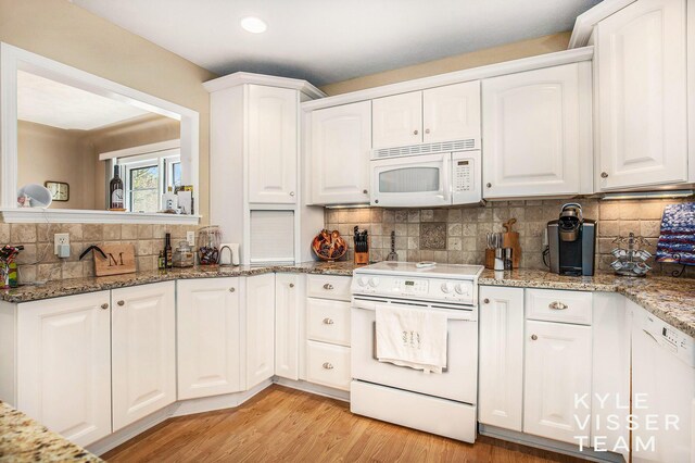 2139 Anderson Dr SE, Grand Rapids, MI 49506 - kitchen featuring white cabinets, light wood-style flooring, decorative backsplash, white appliances, and light stone counters