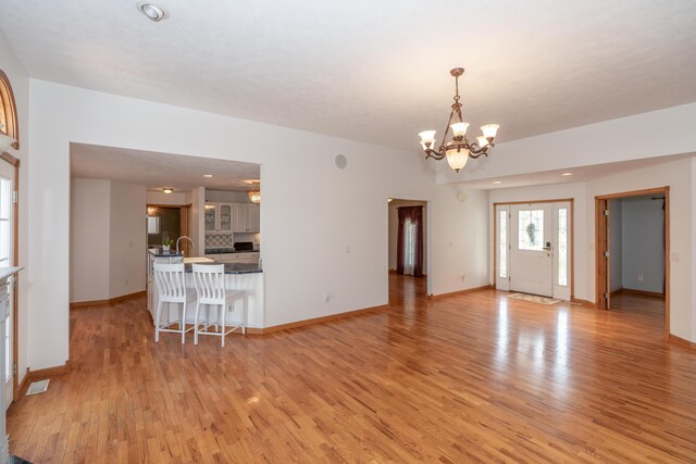 1060 Briarwood Ct, Norton Shores, MI 49441 - living room featuring light wood finished floors, baseboards, an inviting chandelier, and visible vents