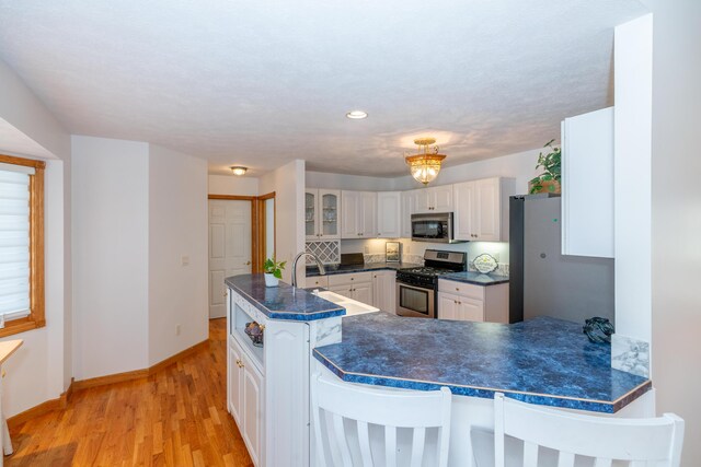 1060 Briarwood Ct, Norton Shores, MI 49441 - kitchen featuring stainless steel appliances, baseboards, light wood-style floors, and dark countertops