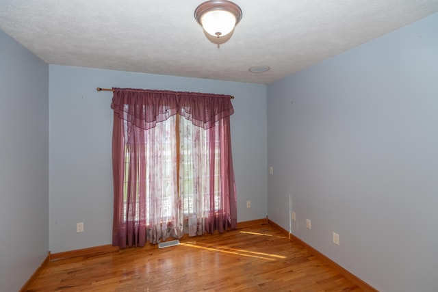 1060 Briarwood Ct, Norton Shores, MI 49441 - empty room with baseboards, wood finished floors, and visible vents