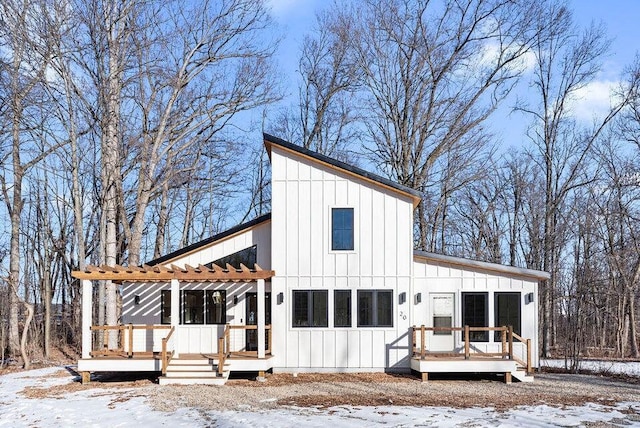 snow covered property featuring a pergola, a deck, and board and batten siding