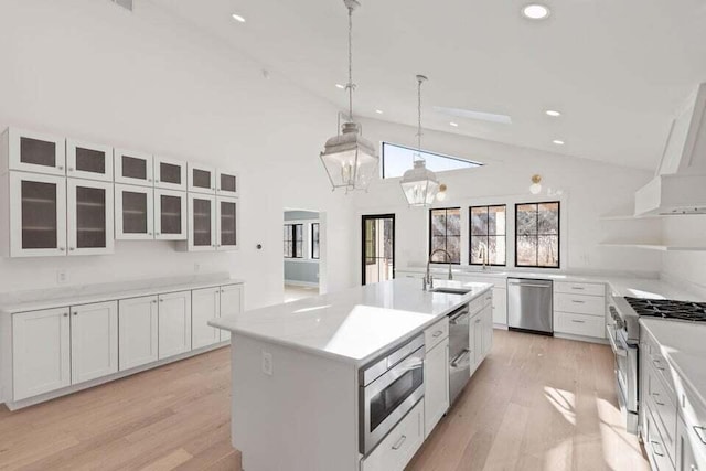 kitchen featuring stainless steel appliances, a center island with sink, recessed lighting, white cabinetry, and wall chimney range hood