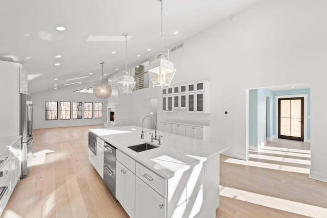 kitchen with white cabinets, a sink, open floor plan, recessed lighting, and appliances with stainless steel finishes