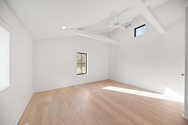 empty room with baseboards, vaulted ceiling, light wood finished floors, and plenty of natural light