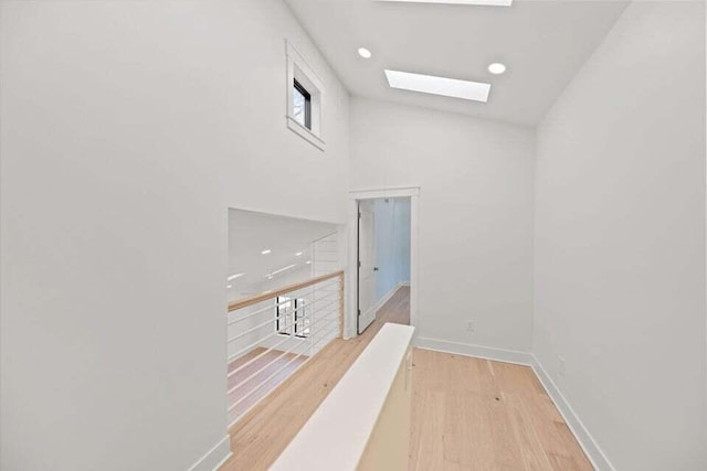 corridor with recessed lighting, wood finished floors, a skylight, and baseboards