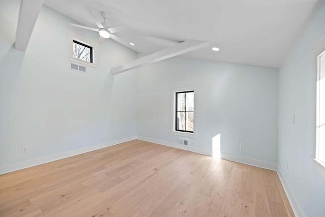empty room with lofted ceiling, visible vents, light wood finished floors, and a healthy amount of sunlight