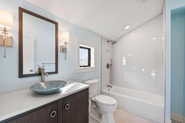 bathroom featuring vaulted ceiling, toilet, vanity, and bathtub / shower combination