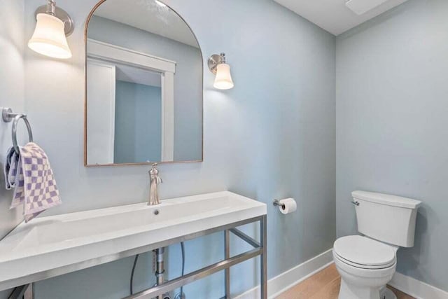 bathroom featuring toilet, wood finished floors, and baseboards