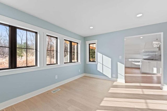 empty room featuring wood finished floors, a wealth of natural light, and baseboards