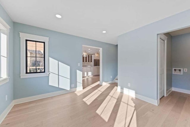 spare room featuring light wood-type flooring, baseboards, and recessed lighting