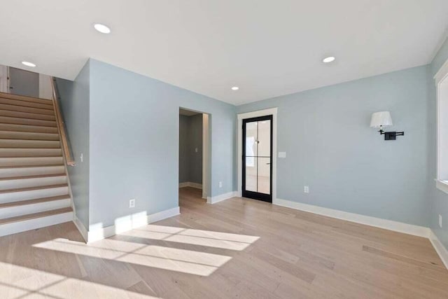 unfurnished living room with light wood finished floors, baseboards, recessed lighting, and stairway