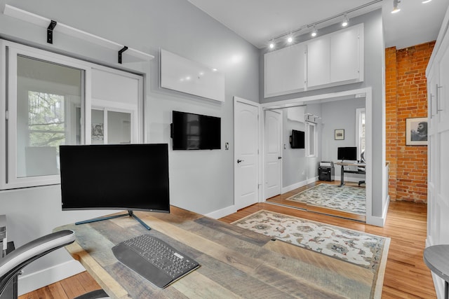113 S Fourth Ave Unit 6, Ann Arbor, MI 48104 - bedroom featuring an office area, track lighting, light wood finished floors, brick wall, and baseboards