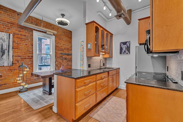 113 S Fourth Ave Unit 6, Ann Arbor, MI 48104 - kitchen with light wood-type flooring, baseboards, a sink, dark stone countertops, and glass insert cabinets