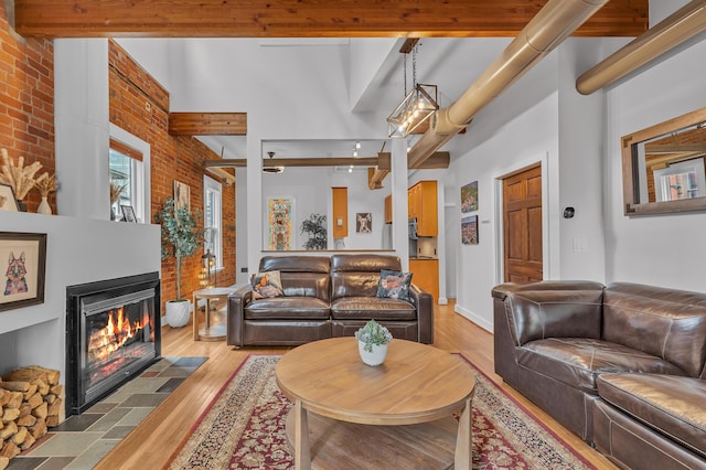 113 S Fourth Ave Unit 6, Ann Arbor, MI 48104 - living area with beam ceiling, light wood-style flooring, a fireplace with flush hearth, brick wall, and a high ceiling