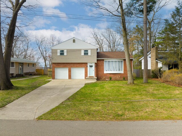 tri-level home featuring a front lawn, driveway, fence, brick siding, and an attached garage