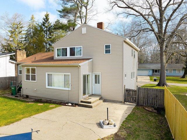 back of house featuring a chimney, fence, and a lawn