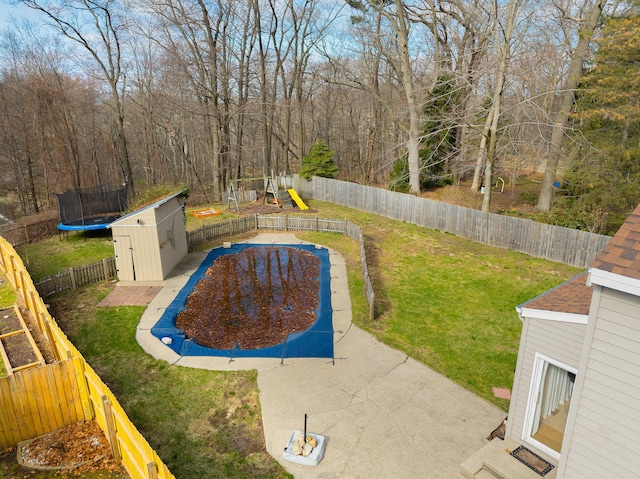 view of swimming pool with a shed, a playground, a trampoline, a lawn, and a fenced backyard