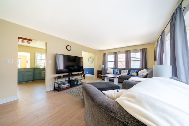 living area with plenty of natural light, light wood-style flooring, and baseboards