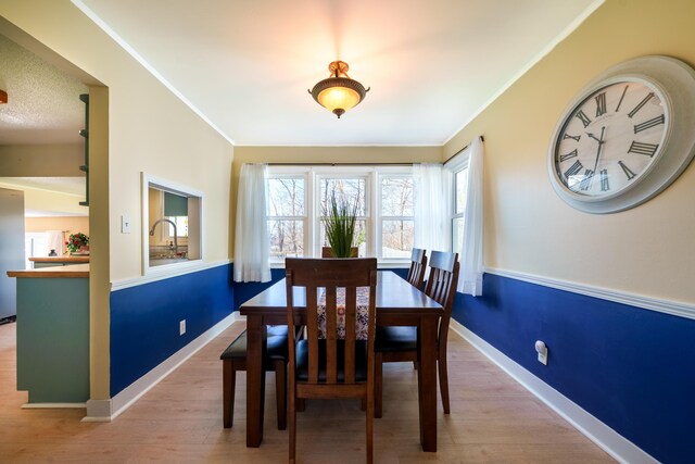 dining room featuring baseboards, wood finished floors, and ornamental molding