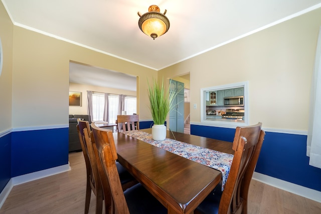 dining area featuring wood finished floors, crown molding, and baseboards