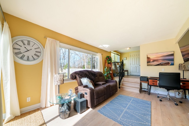 living room with baseboards, light wood-style floors, and stairway