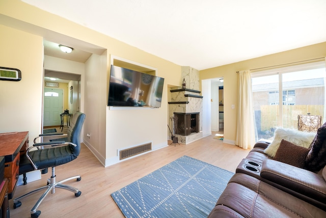 living room featuring baseboards, wood finished floors, visible vents, and a fireplace