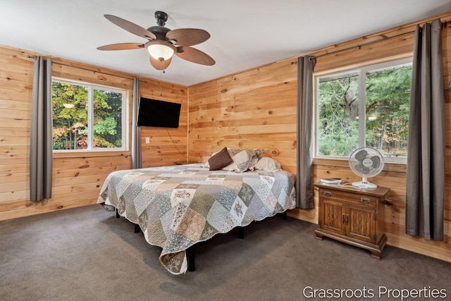 bedroom featuring wood walls, carpet flooring, and multiple windows