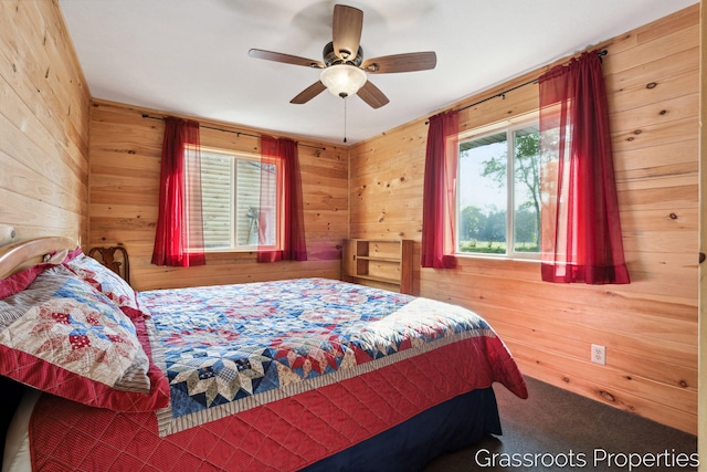 carpeted bedroom featuring wooden walls and a ceiling fan