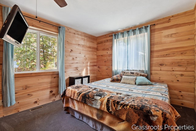 bedroom with wood walls, visible vents, and carpet