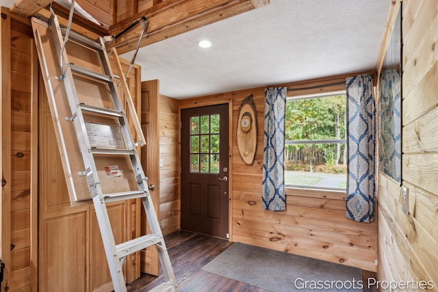 entrance foyer with recessed lighting, a textured ceiling, wood walls, and dark wood-style floors