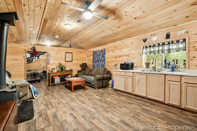 living room with lofted ceiling, light wood finished floors, a wood stove, and wooden walls